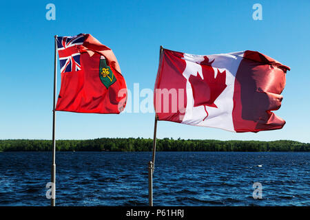 Le bandiere della provincia di Ontario e Canada battenti dal lago di marmo in Ontario, Canada. Il canadese bandiere porta una foglia di acero emblema. Foto Stock