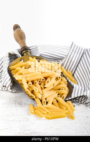 Pasta tipo penne rigate in rame depositante, su sfondo bianco. Foto Stock