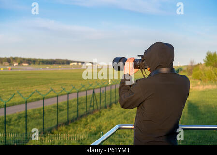 GDANSK, Polonia - 5 Maggio 2018: Fotografo tenendo la lente della videocamera e prendere foto. Aeroporto Lech Walesa in background. Foto Stock