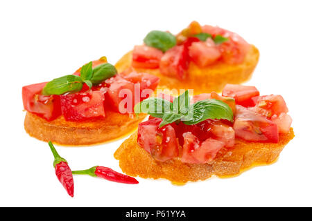 Saporito gustoso pomodoro tagliato a pezzetti su baguette tostato guarnito con basilico e peperoni, Italiano antipasti bruschetta, isolati su sfondo bianco Foto Stock