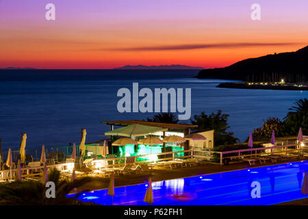 Una piscina e bar sul mare al tramonto in estate a Piombino di fronte all'Isola d'Elba, Italia Foto Stock