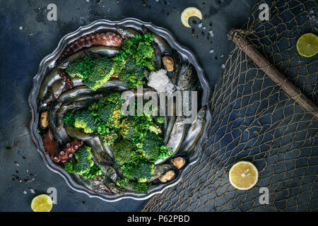 Crudo di pesce misto su un piatto d'argento, sfondo scuro, copyspace Foto Stock