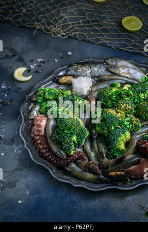 Crudo di pesce misto su un piatto d'argento, sfondo scuro Foto Stock