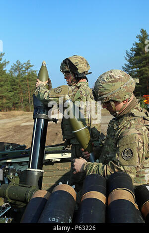 Pvt. La selce Croy (sinistra), un fuoco indiretto fantassin assegnato alla sede centrale e sede di truppe, 3° Stormo, 2° reggimento di cavalleria pende un mortaio round da un Stryker scontri armati il veicolo in una posizione difensiva come Spc. Jeremy Courville si prepara a mano di lui il prossimo round, durante un combinato di bracci vita difensivo-fire esercizio incorporante gli alleati lettone, 7 Aprile a Adazi Base Militare, Lettonia. In precedenza durante la settimana, lettone e soldati americani hanno scavato le posizioni di combattimento in preparazione per la prima gamba dell'evento di formazione. Il live-fire incluso 120mm e 80mm mortai, M2 50 calibro ma Foto Stock