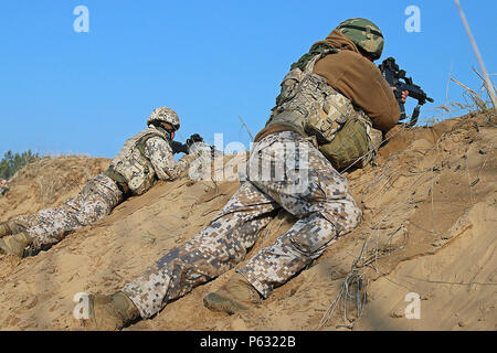 Soldati lettoni si impegna con bersagli durante un combinato di bracci vita difensivo-fire esercizio con i soldati della sede centrale e sede di truppe, 3° Stormo, 2° reggimento di cavalleria, 7 Aprile a Adazi Base Militare, Lettonia. A questo punto lo scenario il nemico è stato avanzamento, così soldati lettoni advanced fino a sand hill da malta di posizione di sparo per impegnare i bersagli con fuoco di armi leggere. (U.S. Esercito foto di Sgt. Paige Behringer, decimo premere Camp la sede centrale) Foto Stock