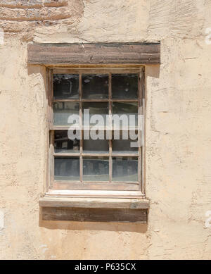 Il legno vecchio finestra incorniciata con dodici vetri, impostato in un muro di adobe Foto Stock