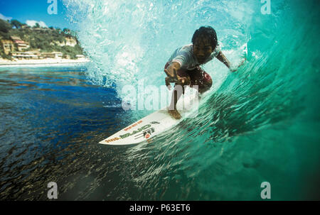 Surfista Balinese in sella alla canna del verde onda surf a Bingin, Bali Foto Stock