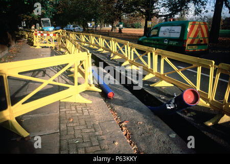 Plastica di sicurezza barriera attorno a una trincea per tubo di acqua in posa per collegamenti nazionali in Wandsworth, Londra, Regno Unito Foto Stock