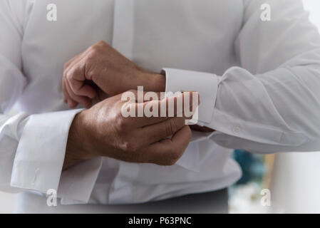 Un groom mettendo sul bracciale-links come egli si veste formale di usura. Lo sposo la tuta Foto Stock