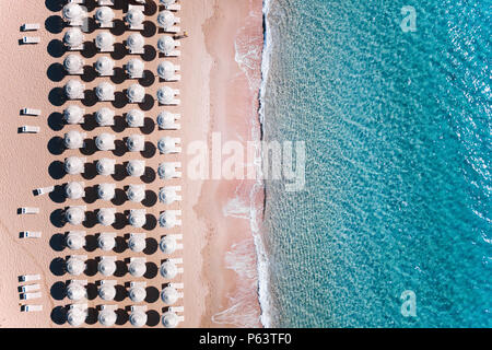 Vista aerea del fantastico mare turchese con bianchi ombrelloni e sedie a sdraio. Bella e soleggiata giornata estiva in Sardegna, Mare Mediterraneo, Italia. Foto Stock
