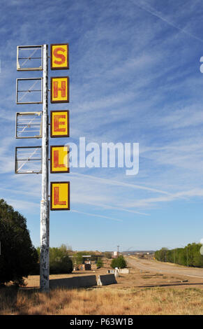 Un alto segno di Shell si trova di fronte a una chiusa e abbandonata arresto carrello lungo il percorso 66 in Tucumcari, Nuovo Messico. Foto Stock