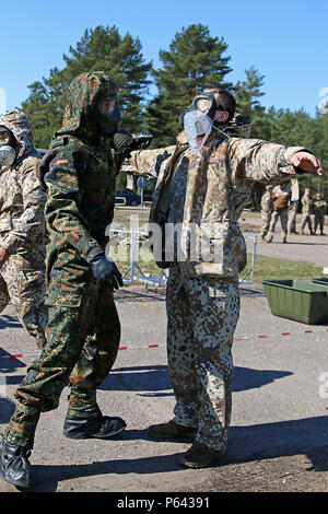 Un soldato tedesco che simula le procedure di decontaminazione su un lettone soldato durante una dimostrazione per illustri visitatori e i dirigenti senior, wrapping up estate scudo XIII, 28 aprile a Adazi Base Militare, Lettonia. Soldati provenienti da cinque Organizzazione del Trattato del Nord Atlantico nazioni, compresa la Lettonia, Canada, Germania, Lituania e degli Stati Uniti sono state conducendo una ampia gamma di corsi di formazione insieme durante il periodo estivo la protezione XIII, un anno per un periodo di due settimane di interoperabilità lungo evento di formazione in Lettonia. Visitatori inclusi i cinque paesi partecipanti Oltre ai rappresentanti provenienti dalla Polonia e Finlandia. (U.S. Un Foto Stock