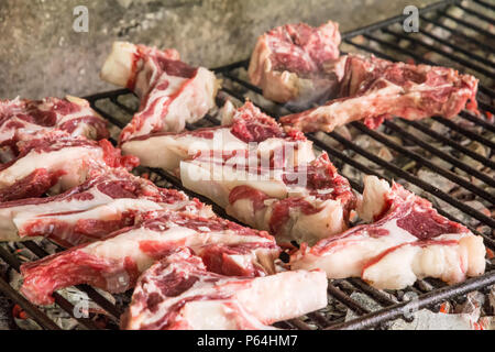 Grigliata di costolette di capra. Arrosto di carne su un barbecue in mattoni tipica barbecue in Sardegna, Italia. Messa a fuoco selettiva Foto Stock