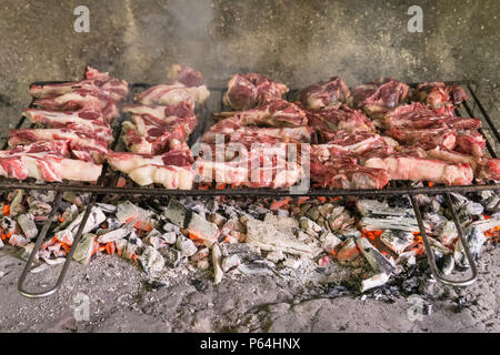 Grigliata di costolette di capra. Arrosto di carne su un barbecue in mattoni tipica barbecue in Sardegna, Italia. Messa a fuoco selettiva Foto Stock