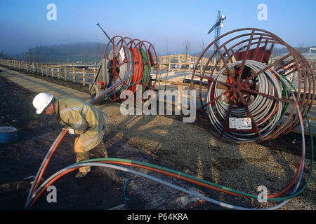 Bobine di fibre ottiche essendo spinto a terra da un lavoratore del sito. Foto Stock