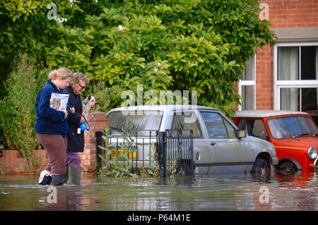 Una vecchia signora con il suo cane è aiutato da un giovane del prossimo in una strada residenziale sotto inondazione in Longford, Gloucester, Regno Unito, 2007 Foto Stock