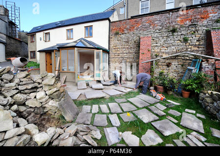 Costruttori di lay out di pietra naturale in lastre nella pianificazione di un patio, GLOUCESTERSHIRE REGNO UNITO Foto Stock