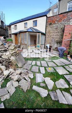 Costruttori di lay out di pietra naturale in lastre nella pianificazione di un patio, GLOUCESTERSHIRE REGNO UNITO Foto Stock