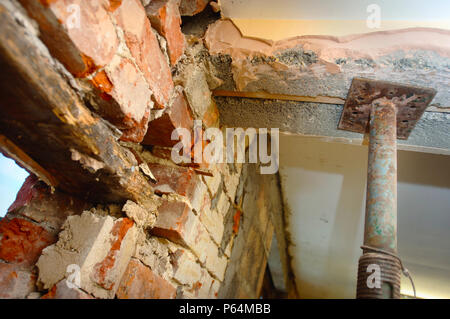 Puntelli Acrow tenendo un architrave di calcestruzzo in cui una porta con un vecchio architrave in legno ha bisogno di essere riparato Foto Stock