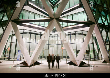 Ufficio i lavoratori che lasciano la Swiss Re Tower di notte a Londra REGNO UNITO Foto Stock