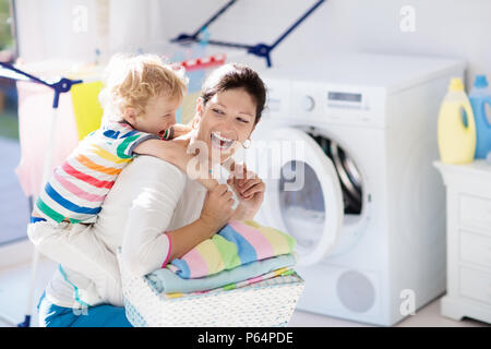 Madre e bambini nella stanza lavanderia con lavatrice o asciugatrice.  Incombenze familiari. Moderni dispositivi domestici e di detersivo di  lavaggio in bianco sunny hom Foto stock - Alamy