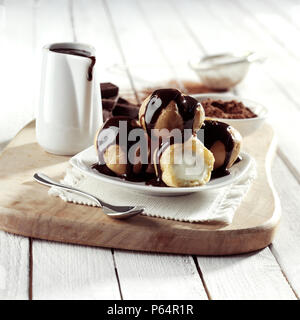 Profiteroles coperti in salsa di cioccolato Foto Stock