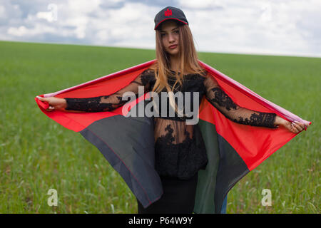 Giovane bella ragazza ucraina con un ottima figura in un nero abito corto detiene un nazionali ucraine red flag nero Foto Stock