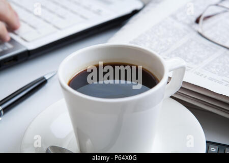 Imprenditore in esecuzione e una tazza di caffè su di lui desktop Foto Stock