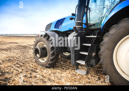 Una ruota da un trattore lavora nel campo vicino. Il concetto di lavoro sul campo e l'agricoltura. Foto Stock