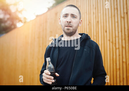 Uomo Barbuto tenendo la bottiglia di cola. Foto Stock