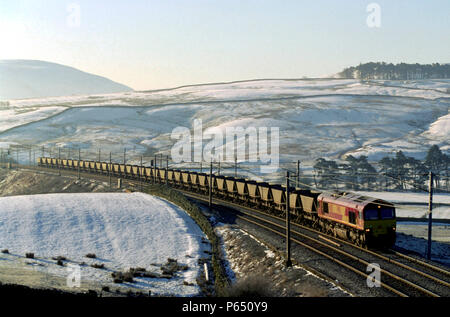 Una classe 66 locomotore traina un rastrello di carbone carri presso Greenholme in Cumbria. Regno Unito. Foto Stock