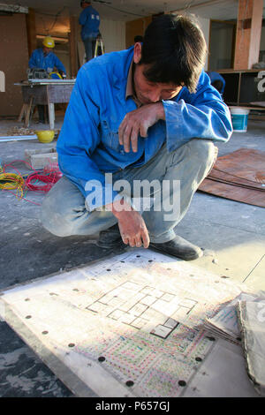 Un lavoratore edile consulta un piano di disposizione per l'installazione del cablaggio in una nuova torre di uffici nel centro di Pechino. Foto Stock