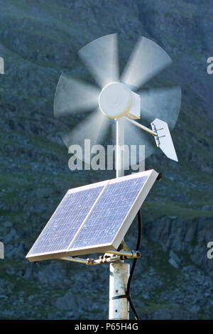 Un solare pannello elettrico e la turbina eolica essendo utilizzata per l'alimentazione di un neon di cartello stradale su Kirkstone Pass, Lakle distretto, UK. Foto Stock