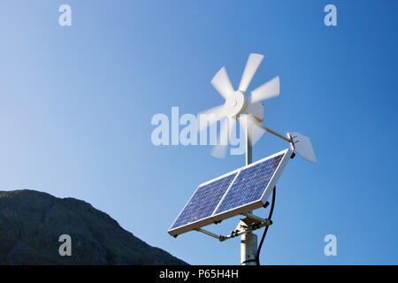 Un solare pannello elettrico e la turbina eolica essendo utilizzata per l'alimentazione di un neon di cartello stradale su Kirkstone Pass, Lakle distretto, UK. Foto Stock