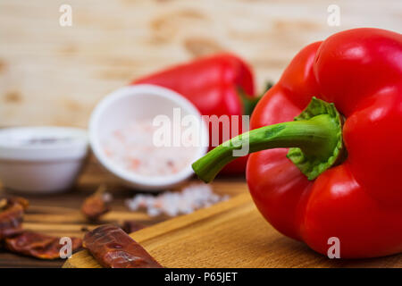 Peperoni, pomodori, sale, spezie diverse su sfondo di legno Foto Stock