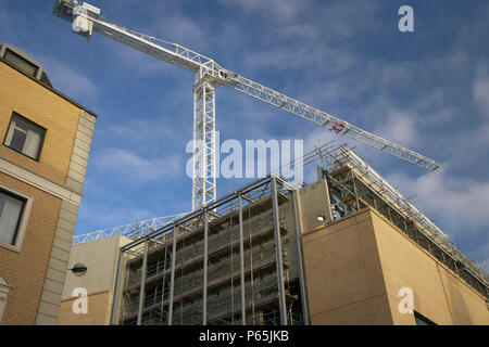 Nuovo blocco di ufficio in costruzione con gru a torre. Foto Stock
