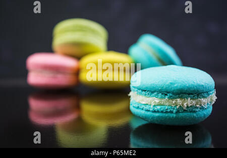 Deliziosi macaron colorati torte su sfondo scuro Foto Stock