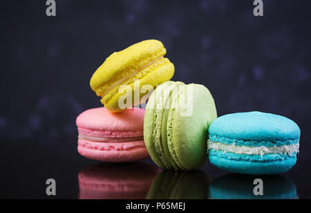 Deliziosi macaron colorati torte su sfondo scuro Foto Stock