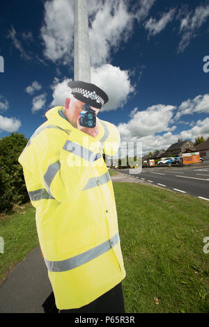 Una vita di taglio di dimensioni al di fuori di un funzionario di polizia, attaccato ad un lampione, tenendo un autovelox sulla periferia del grande villaggio di Milnthorpe in Cumbr Foto Stock