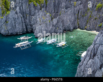 Antenna fuco vista delle barche tradizionali in una baia stretta con una bella spiaggia di sabbia e le torreggianti, frastagliate scogliere di calcare Foto Stock