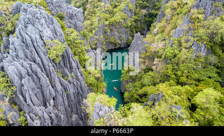 Antenna vista drone di kayak all'interno di un bel poco profonda laguna tropicale circondata da scogliere frastagliate e jungle (piccola laguna, El Nido) Foto Stock