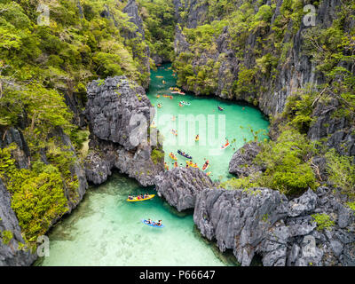 Antenna vista drone di kayak all'interno di un bel poco profonda laguna tropicale circondata da scogliere frastagliate e jungle (piccola laguna, El Nido) Foto Stock