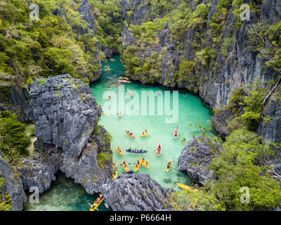 Antenna vista drone di kayak all'interno di un bel poco profonda laguna tropicale circondata da scogliere frastagliate e jungle (piccola laguna, El Nido) Foto Stock