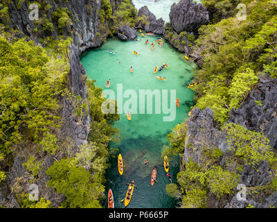 Antenna vista drone di kayak all'interno di un bel poco profonda laguna tropicale circondata da scogliere frastagliate e jungle (piccola laguna, El Nido) Foto Stock