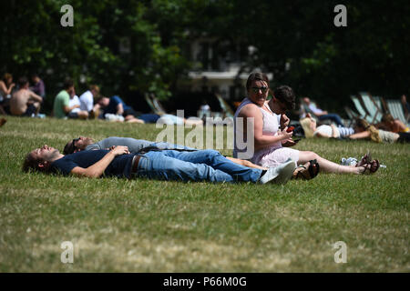 Popolazione gode di un clima caldo in Green Park, Londra. I britannici sembrano godere le temperature più calde dell'anno per il quarto giorno in una fila di questa settimana con il mercurio prevista per elevarsi a 32C (89.6F). Foto Stock