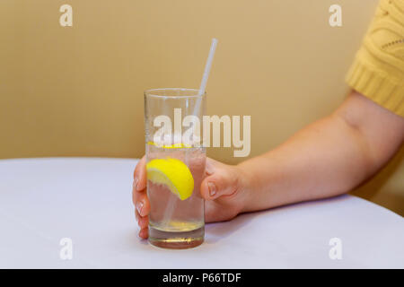 Donna mano che tiene un bicchiere di soda con il limone Foto Stock