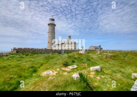 Il vecchio faro di luce su Lundy Island visto dal cimitero. Il Lighthouse keepers' cottage è ora utilizzato come alloggio per le vacanze Foto Stock