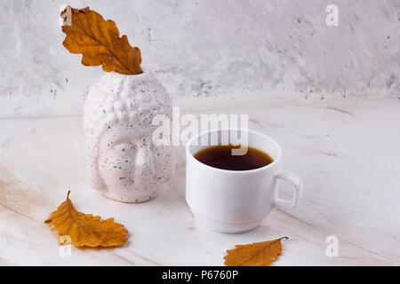 Testa di Budda e secco foglie di giallo autunno still life con spazio di copia Foto Stock
