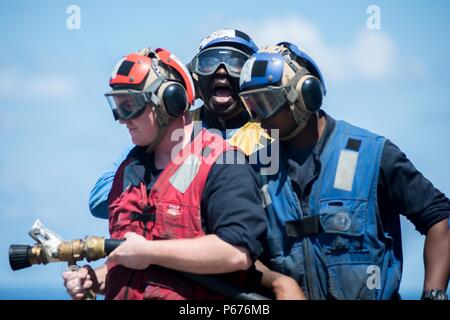 160519-N-EH218-023 sul Mare del Sud della Cina (19 maggio 2016) - Boatswain compagno del 3° di classe Layebangali Francesco Soumaoro dà istruzioni al suo team flessibile durante un crash e recupero seminatrice sul ponte di volo dell'guidato-missili cruiser USS Mobile Bay (CG 53). Fornire una forza di pronto il supporto di sicurezza e stabilità nella Indo-Asia-pacifico, Baia di Mobile è operativo come parte del John C. Stennis Strike gruppo e grande parco verde su un pianificate regolarmente 7 Distribuzione flotta. (U.S. Foto di Marina di Massa lo specialista di comunicazione 2a classe Ryan J. Batchelder/rilasciato) Foto Stock