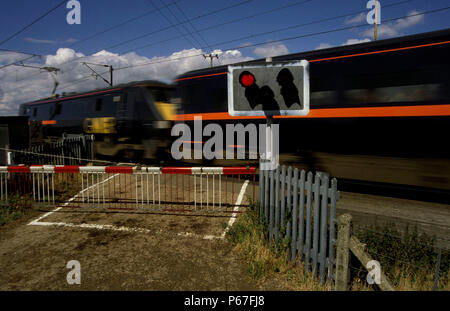 Goccia di barriera a livello rurale incrocio con luci rosse lampeggianti GNER e velocizzando il treno sulla East Coast Main Line. C2000 Foto Stock